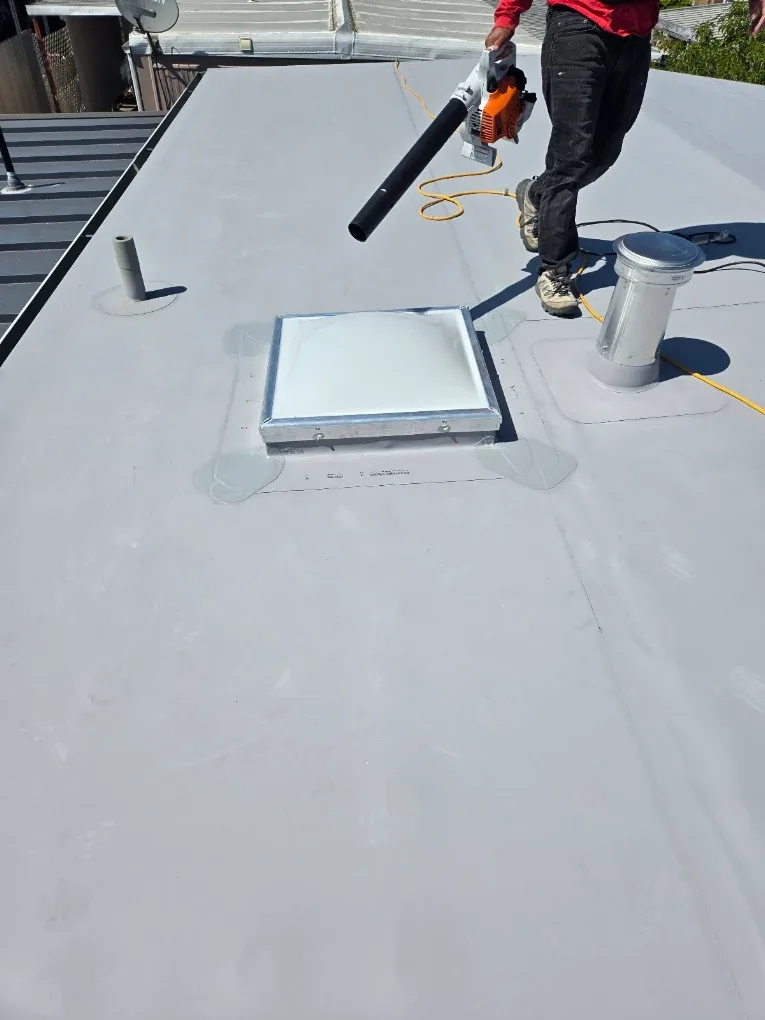 Skylight and pipe flashings on a finished white roof